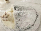Fluffy gray pet bed with a cat inside on a soft white surface.