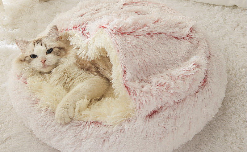 Cat lying in a fluffy pink pet bed 
