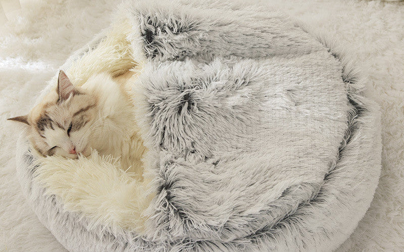 Fluffy pet bed with a cat inside on a soft surface.