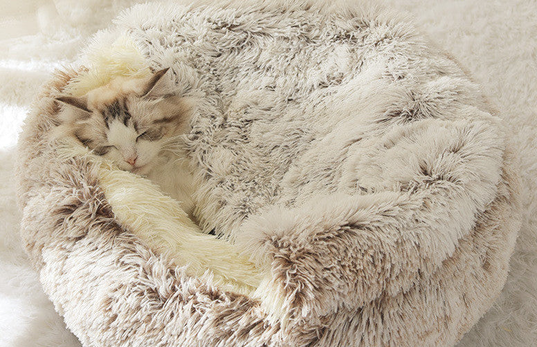 Fluffy pet bed with a cat inside on a soft white background.