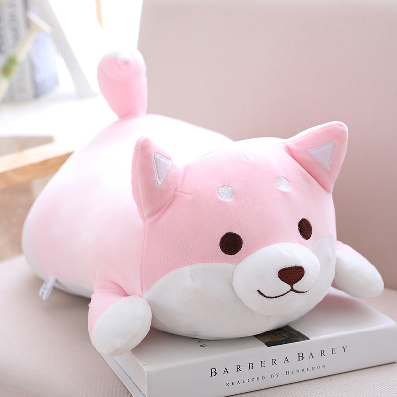 Cute pink and white plush toy resembling a fox on a book with a blurred background
