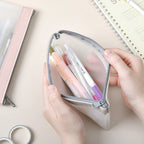 Hand holding a small pouch with colorful pens on a light surface