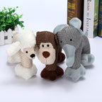 Three knitted animal toys (bear, monkey, elephant) on a white surface with books and a plant in the background.