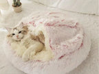 Cat lying in a plush Sakura Pink pet bed on a light-colored floor.