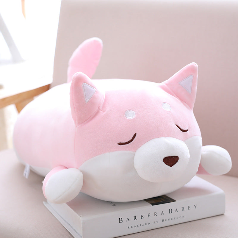 Pink and white plush toy resembling a cat on top of a book with a blurred background