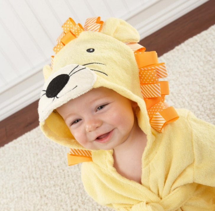 Baby wearing a lion-themed hooded towel on a carpeted floor.
