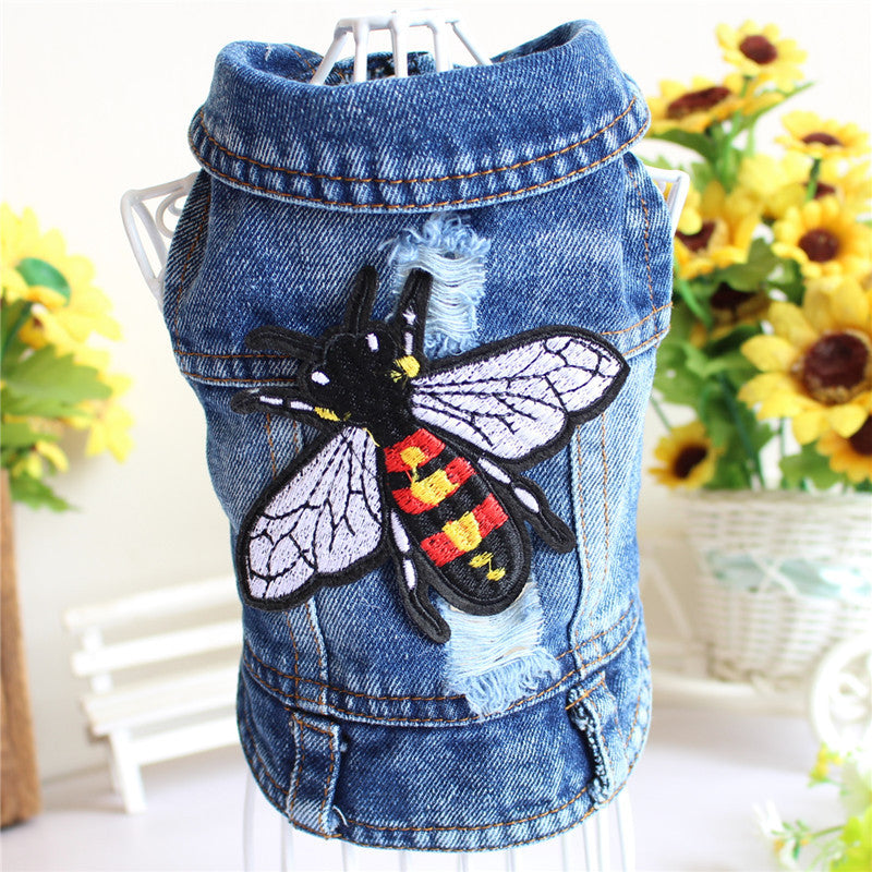 Denim dog vest with a bee patch on a stand with sunflowers in the background