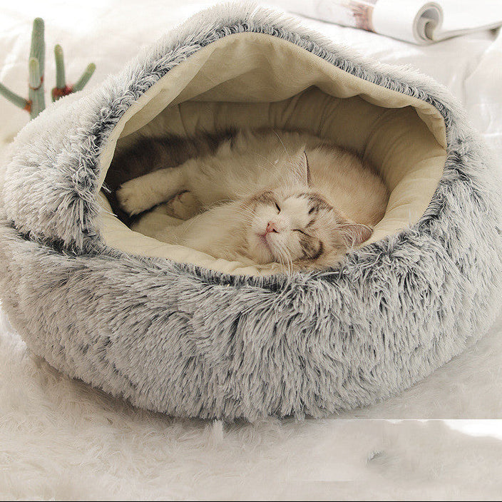 Cat lying in a fluffy gray pet bed on a soft white background.