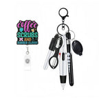 A keychain-style selfie ID badge reel set on a plain white background. The set includes a black keychain clip, a white retractable badge reel with a colorful printed sign reading 'coffee SCRUBS AND RUBBER GLOVES,' several black and silver pens, a pair of small scissors, and a black contactless reader card.