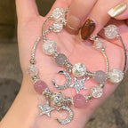 Two bracelets with star and moon charms on a hand