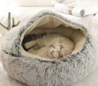 Fluffy gray pet bed with a cat inside on a soft white background