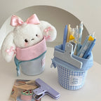 Plush toy with a pink bow and stationery items including pens and a paper punch on a white surface.