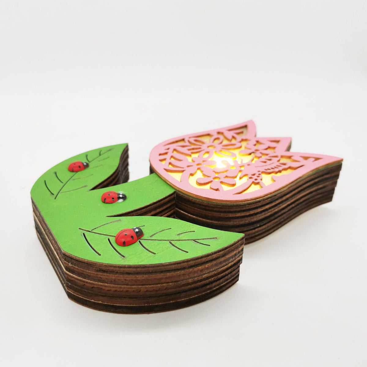 A wooden ladybug-shaped night light with a green leaf body, red ladybugs, and a pink flower-shaped top emitting a warm yellow light, shown on a white background.