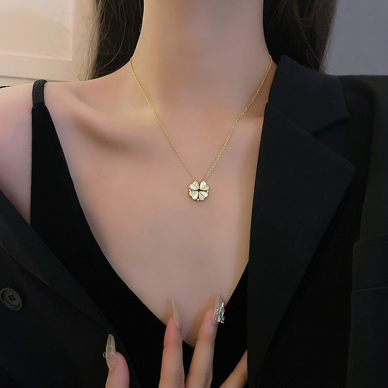 Gold necklace with a clover pendant worn by a person in a black blazer.
