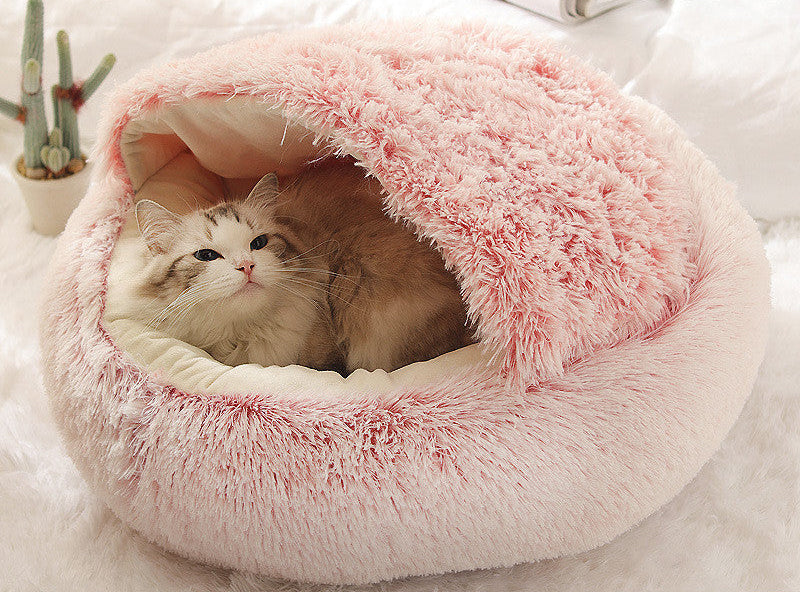 Pink plush pet bed with a cat inside on a white background