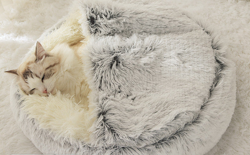 Fluffy pet bed with a cat inside on a soft surface. 