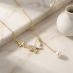 Delicate gold necklace with butterfly and pearl pendant on marble surface