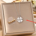 Silver four-leaf clover necklace on a display box with a gold necklace for comparison.