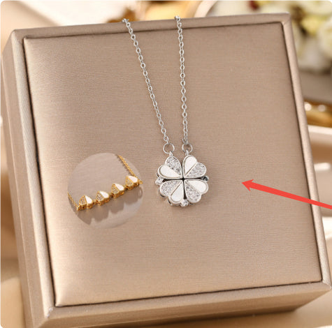 Silver four-leaf clover necklace on a display box with a gold necklace for comparison.