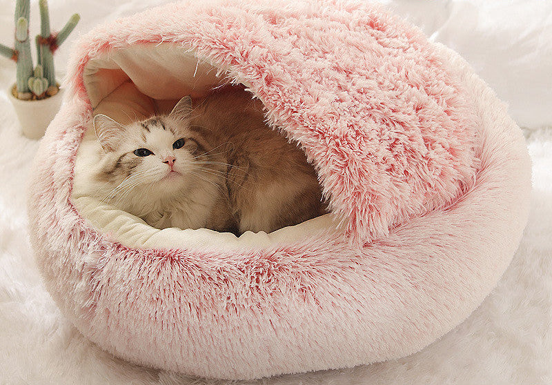 Pink plush pet bed with a cat inside on a light background