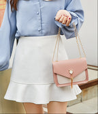 Person wearing a light blue shirt and white skirt holding a pink handbag.