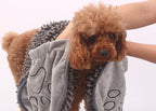 Dog wearing a gray towel with paw prints, held by a person.