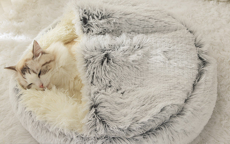 Fluffy pet bed with a cat inside on a soft surface.