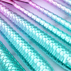 Mermaid scale patterned straws in pink, blue, and green on a light gray background