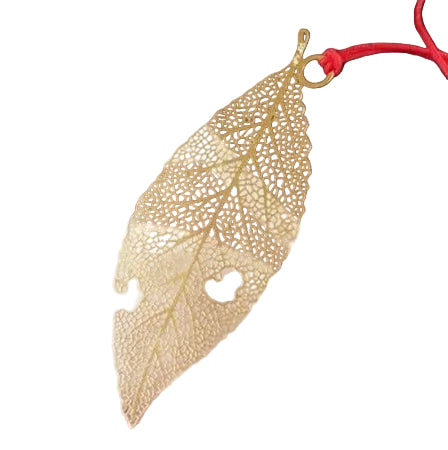 Gold leaf-shaped pendant on a red string on a white background.
