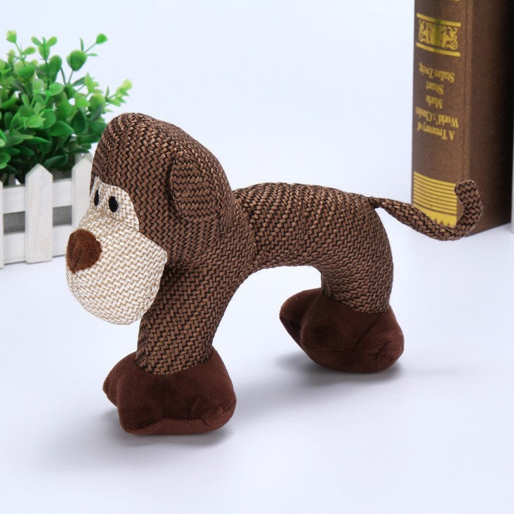 Brown monkey plush toy on a white surface with a book and plant in the background