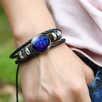 Bracelet with a colorful bead on a wrist against a blurred green background
