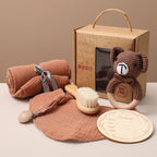 Baby care products including a blanket, toy, and bath items on a beige surface with a brown background.