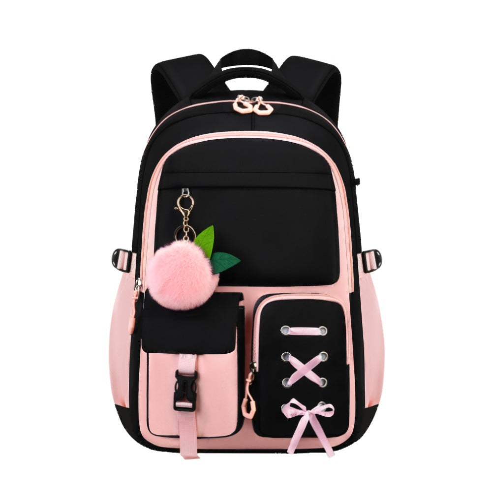 A pink and black backpack with multiple front pockets, decorative metal eyelets, a pink pom-pom keychain with green leaves, and a pink ribbon bow detail on the lower pocket, shown on a plain white background.