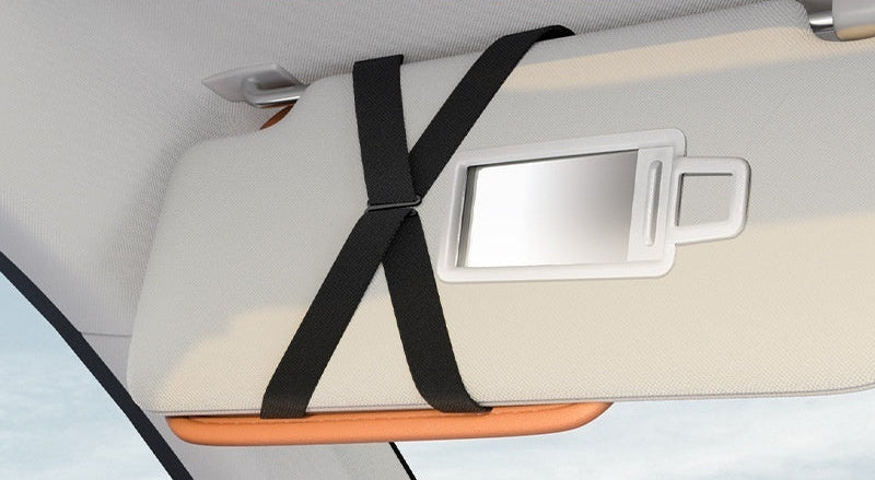 Car visor with a black strap holding a makeup mirror, with text indicating it does not block the mirror.