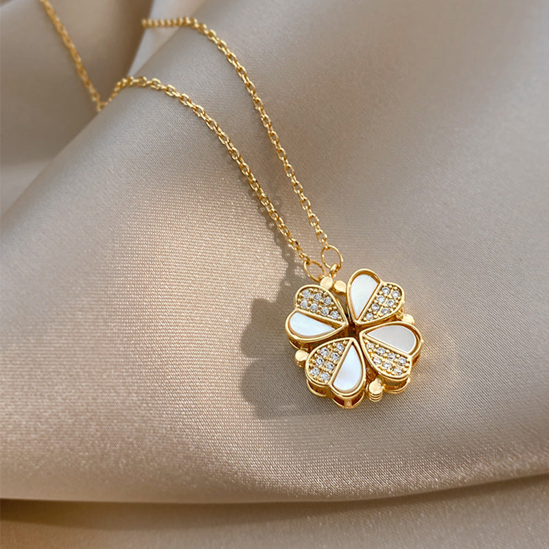Gold necklace with a four-leaf clover pendant on a beige fabric background