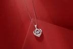 Silver heart-shaped pendant with clear stones on a red background