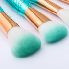 Makeup brushes with gradient green bristles on a light background