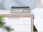 Wireless charger with clock on a nightstand next to a bed