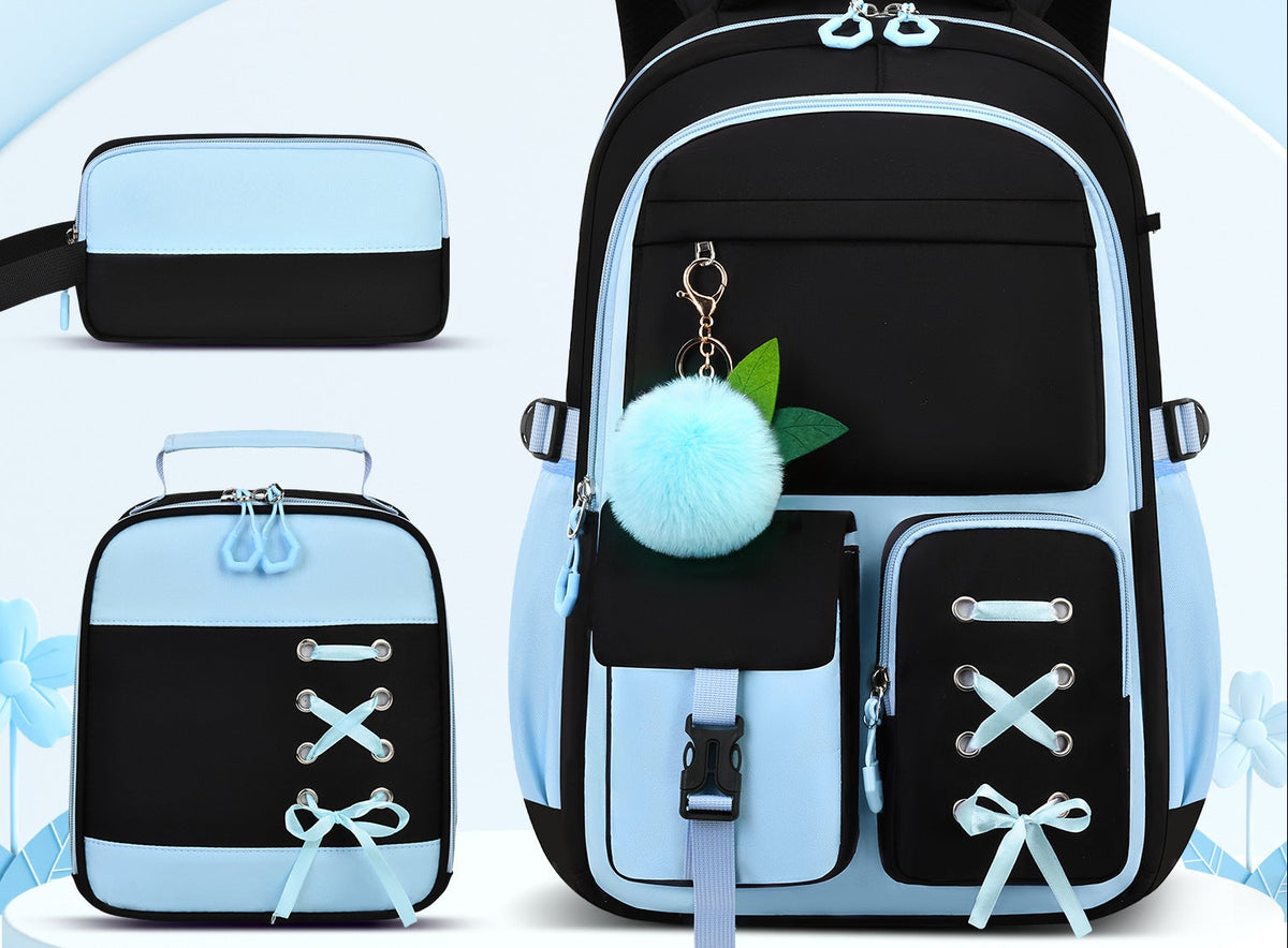 A black and light blue backpack set shown with a matching small pouch and lunch bag on a pale blue graphic background. The main backpack has multiple front pockets, zipper compartments, a fluffy light blue pom-pom charm, and decorative bow details.