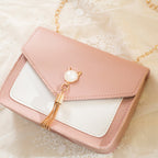 Pink handbag with gold chain and tassel on a light background