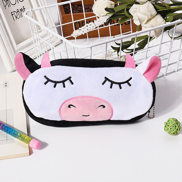 Cute cow-shaped pencil case on a white surface with stationery items.