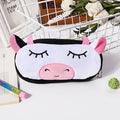Cute cow-shaped pencil case on a white surface with stationery items.