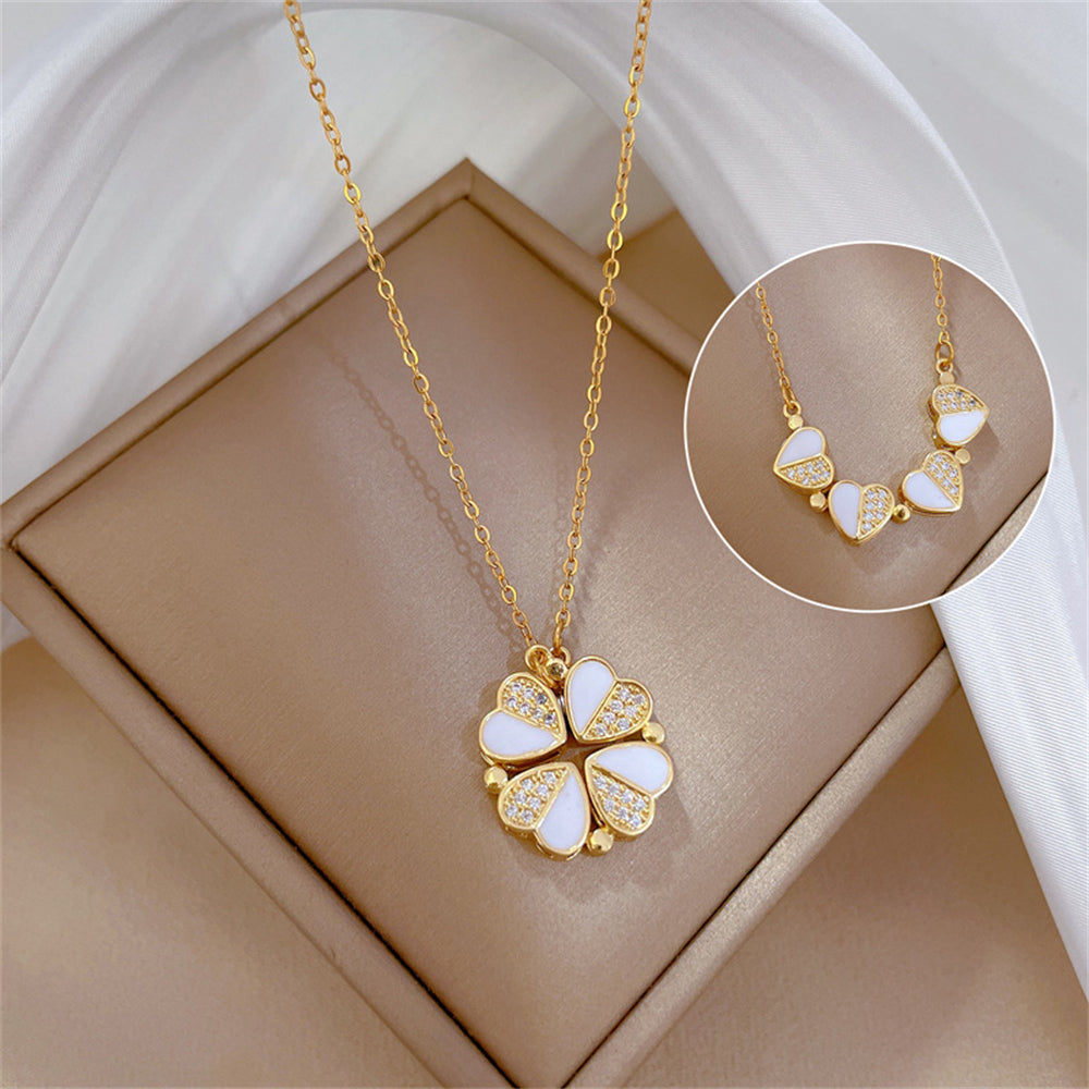 Gold necklace with a clover-shaped pendant on a beige surface