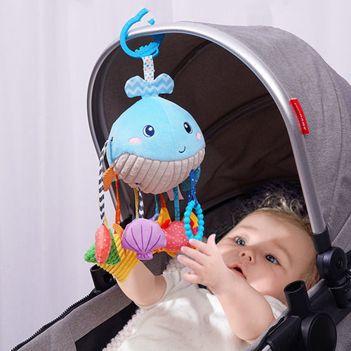 Baby playing with a colorful jellyfish-shaped toy in a stroller.