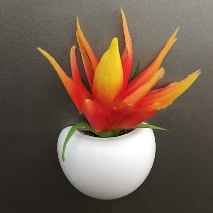 Artificial plant with orange and yellow leaves in a white pot on a dark background